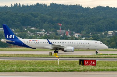 Zürih, İsviçre, 5 Ağustos 2025 SE-RSK SAS İskandinav Havayolları Embraer E195LR uçağı kapıya doğru ilerliyor.