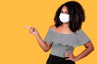 Koruyucu tıbbi maskeli genç siyahi bir kadının stüdyo portresi. Corona gribi salgını, Covid 19 'da kopya için yer var..