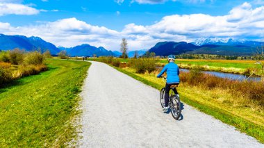 Üst düzey kadın Alouette nehir boyunca Pitt Polder British Columbia, Kanada Maple şehir Ridge'de çevreleyen lezbiyen bisikleti