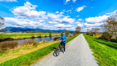 Üst düzey kadın Alouette nehir boyunca Pitt Polder British Columbia, Kanada Maple şehir Ridge'de çevreleyen lezbiyen bisikleti