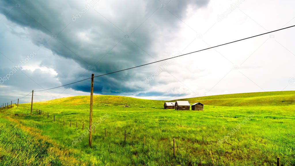Tin Roofed Barns in the wide open Grass Lands of the Nicola Valley, along Highway 5A between Merritt and Kamloops, British Columbia, Canada, under dark threatening sky