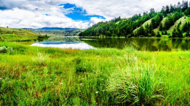 Mavi gökyüzü, bulutlar ve çevredeki dağların Trapp Gölü, Otoban 5a Kamloops ve British Columbia, Kanada içinde Merritt arasında yer alan yumuşak su yüzeyinde yansıtan