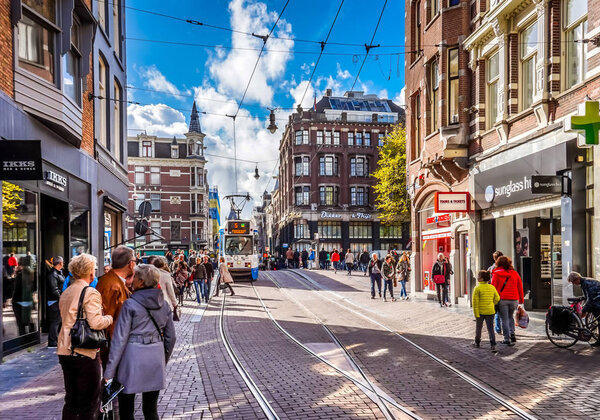 Пешеходы и трамваи на оживленном Leidsestraat в центре Амстердама в хороший октябрьский день
