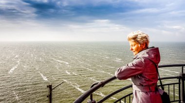 Kıdemli het Ijsselmeer üzerinden Hollanda'da Urk tarihi balıkçı köyü fenerinde üzerinden Fırtınalı hava izlerken kadın