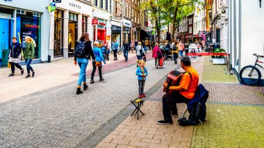 Zwolle, Overijsel/the Netherlands - Oct. 4, 2018: A little girl listening to a busker playing the accordion in the busy Diezerstraat in the center of the historic hanseatic city of Zwolle