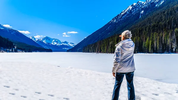 凍ったダフィー湖と湖の周りの雪の頂上の景色を楽しむシニア女性 ブリティッシュコロンビア州ペンバートンとリルルーエット間のハイウェイ99沿いの湖の南端にあるローア山 — ストック写真