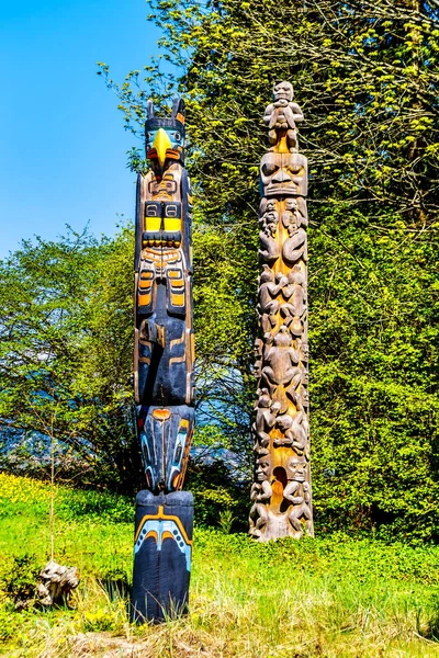 The \'Oscar Maltipi Totem Pole\' and \'Beaver Crest Totem Pole\' in Stanley Park. The second is different as it is unpainted and it\'s main body is circular