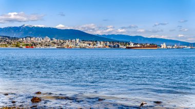 Vancouver. Bc/Kanada-24 Mayıs 2019: Arka planda Seymour Dağı'nın olduğu Stanley Park Seawall yolundan vancouver limanının kuzey kıyısı manzarası