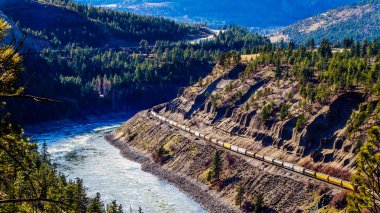 Thompson ve Fraser Nehri Kanyonu'ndaki tüneller boyunca, dik kayalıklar boyunca Thompson ve Fraser Nehirleri'ni takip eden uzun yük trenleri 