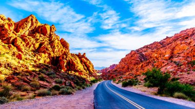 Nevada, ABD'deki Valley of Fire State Park'tan geçerken Mouse Tank'ın Yolu boyunca uzanan parlak kırmızı Aztek kumtaşı kaya oluşumları üzerinde gün doğumu