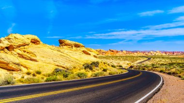 Nevada, ABD'deki Valley of Fire State Park'tan geçerken Beyaz Kubbeler Yolu boyunca uzanan renkli Aztek kumtaşı kaya oluşumları üzerinde gün doğumu