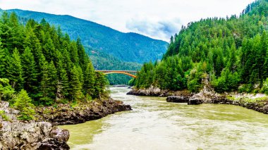 Kudretli Fraser Nehri, Alexandra Köprüsü 'nün kemer biçimli çelik yapısıyla Trans Canada Otoyolu' nda. Nehrin yukarısındaki tarihi İkinci Alexandra Köprüsü 'nden