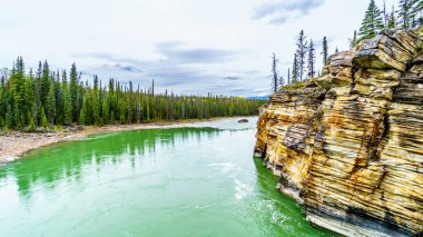 Athabasca Nehri 'nin sessiz turkuaz suyu Jasper Ulusal Parkı, Alberta, Kanada' daki Athabasca Şelalesi 'nden hemen sonra.