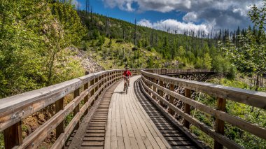 Biking over the Wooden Trestle Bridges of the abandoned Kettle Valley Railway in Myra Canyon near Kelowna, British Columbia, Canada clipart
