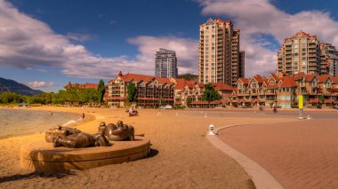 Kelowna, British Columbia/Canada - July 24, 2020: Waterfront at the Rhapsody Plaza with the bronze art display of 5 Sunbathers named 'On the Beach' in the City of Kelowna clipart