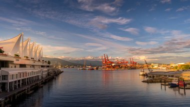 Vancouver, BC / Kanada - 16 Temmuz 2020: Vancouver Konteyner Limanı üzerinde gün batımı ve Kanada Place Cruise Terminali ile Rıhtım Kıyısı Skytrain ve Seabus Terminali arasında