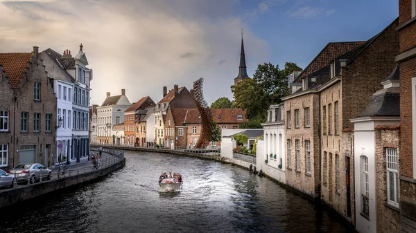2018年9月18日 ベルギー ブルージュの歴史的都市 サンアナレイ運河沿いの運河船で 右側には製鉄所の彫刻と聖アンナ教会の塔があります — ストック写真