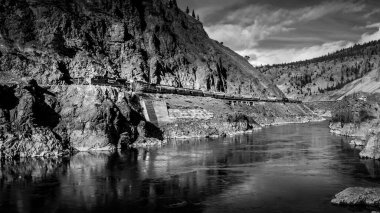 Spences Köprüsü, BC / Kanada-14 Şubat 2015: Thompson Nehri Kanyonu 'nun dik uçurumları boyunca seyahat eden Uzun Kargo Treninin Siyah ve Beyaz Fotoğrafı