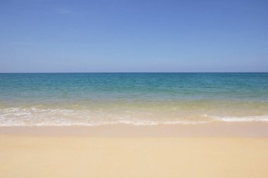 Idyllic kristal plajı ve lüks otelin önündeki deniz suyu, çekici berrak deniz, tatil zamanı güneşlenirken doğa sahili arkaplanı, berrak mavi denizden el sallama ve ince kum. 