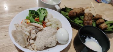 Dilimlenmiş orta pişmiş yumurta ve çeşitli sebzelerle servis edilen organik tavuk göğsü beyaz tabak, ev yapımı, taze market restoranı, yemek menüsü reklam geçmişleri üzerine havuç, bezelye brokoli.