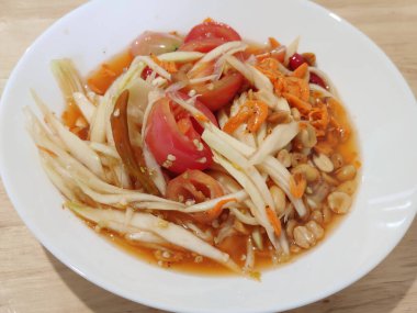 Beyaz tabakta servis edilen havuçlu, fıstıklı, kurutulmuş karides ve domatesli Papaya salatası sosu. Taze Tayland sokak restoranının ünlü gizli tarifi. Yemek tasarımcısı menüsü.