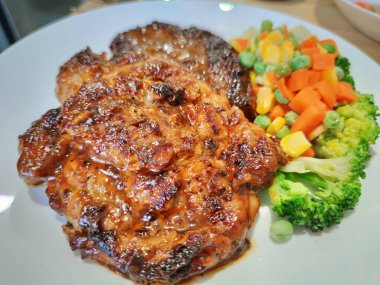 Dilimlenmiş organik domuz eti, çeşitli rengarenk sebzelerle süslenmiş biftek, ahşap masada beyaz tabakta servis edilen bezelye aromalı limon sosu, sokak yemekleri restoranının ünlü gizli tarifi, yemek stilisti.