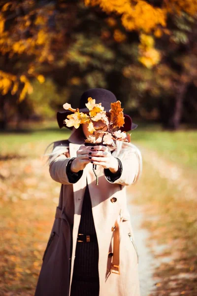 Woman Covering Her Face with Autumn Leaves