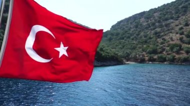 Ağır çekim. Türk Bayrakları rüzgarda sallayarak. Deniz ve dağlar arka plan üzerinde.