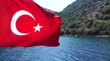 Ağır çekim. Türk Bayrakları rüzgarda sallayarak. Deniz ve dağlar arka plan üzerinde.