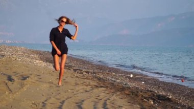 Yavaş çekim. Gün batımında deniz kıyısında çalışan çekici kadın.