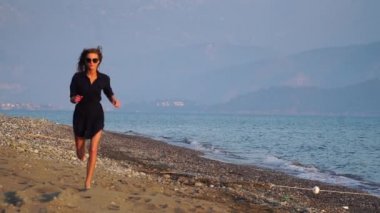 Yavaş çekim. Gün batımında deniz kıyısında çalışan çekici kadın.