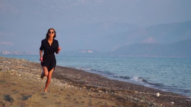 Yavaş çekim. Gün batımında deniz kıyısında çalışan çekici kadın.