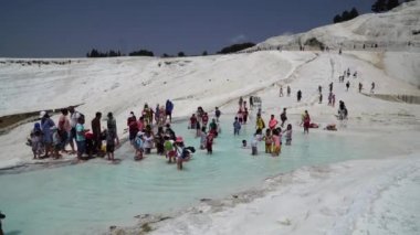 Pamukkale'deki traverten havuzlarını ya da Pamuk Kale'yi ziyaret eden bir turist kalabalığı. Türkiye, Pamukkale, 3 Mayıs 2018.