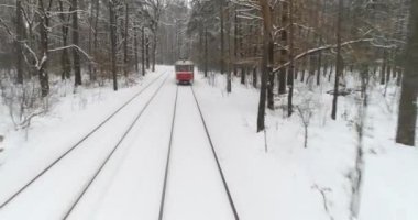 Havadan çekilen görüntüler. Karla kaplı ormanda kırmızı elektrikli tramvay sürmek. 4k