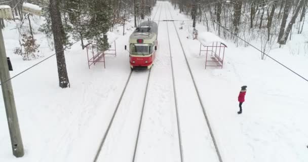 Запись Воздуха Красный Электрический Трамвай Проезжает Через Заснеженный Лес — стоковое видео