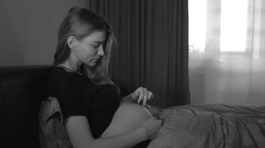 Yatakta karnına dokunan hamile bir kadın. 4k.