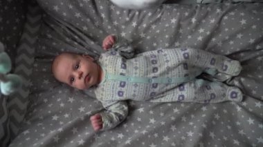 Bebek çocuk yatağında döner oyuncağa bakıyor. 4K.