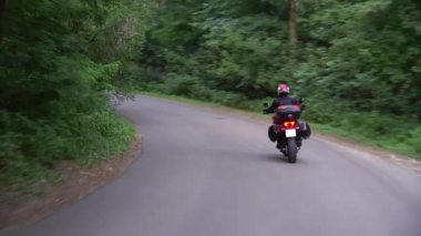 Genç motorcu ülke yolda motosiklet sürme. Sürekli gimbal atış. 4k.