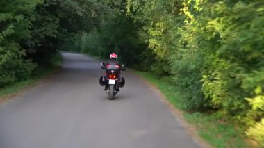 Orman yolunda motosikletsüren genç motorcu. Sürekli gimbal atış. 4k.