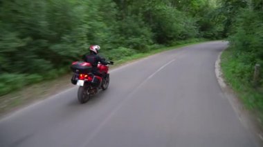 Orman yolunda motosikletsüren genç motorcu. Sürekli gimbal atış. 4k.