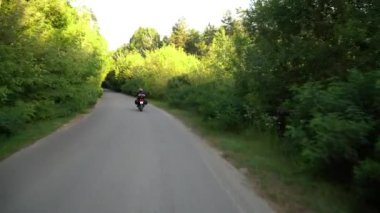 Orman yolunda motosikletsüren genç motorcu. Sürekli gimbal atış. 4k.