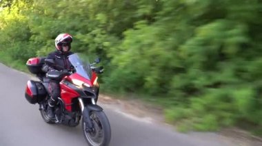 Orman yolunda motosikletsüren genç motorcu. Sürekli gimbal atış. 4k.