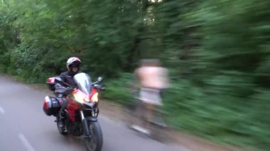 Orman yolunda motosikletsüren genç motorcu. Sürekli gimbal atış. 4k.