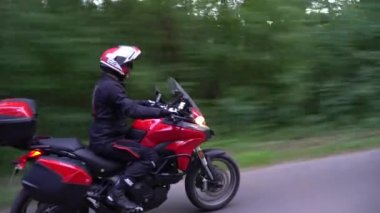 Orman yolunda motosikletsüren genç motorcu. Sürekli gimbal atış. 4k.