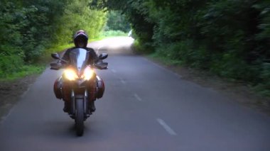 Orman yolunda motosikletsüren genç motorcu. Sürekli gimbal atış. 4k.