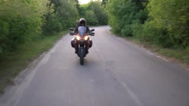 Orman yolunda motosikletsüren genç motorcu. Sürekli gimbal atış. 4k.