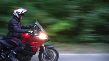 Orman yolunda motosikletsüren genç motorcu. Sürekli gimbal atış. 4k.