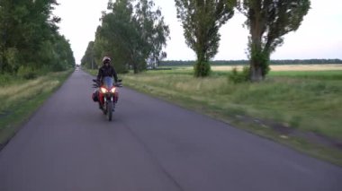 Genç motorcu ülke yolda motosiklet sürme. Sürekli gimbal atış. 4k.