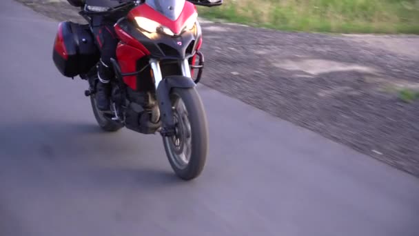 田舎道でオートバイに乗る若いバイカー 着実なジンバルショット — ストック動画