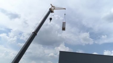 Havadan görünüm. Şantiyedeki vinç manipülatörü yükü kaldırır. 4k
